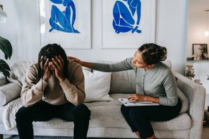 Homme qui pense trop et tient sa tête entre ses main. Une femme le coache.