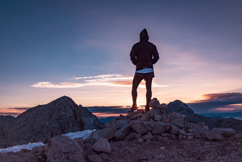 Personne en randonnée, arrivée tout en haut de son objectif de montagne, contemplant la vue