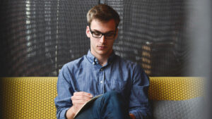 Homme hypersensible assis en train de travailler sur un divan