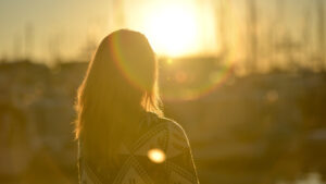 Femme de dos face au soleil couchant
