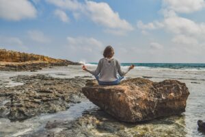 Femme pratiquant le yoga zen sur un rocher face à la mer
