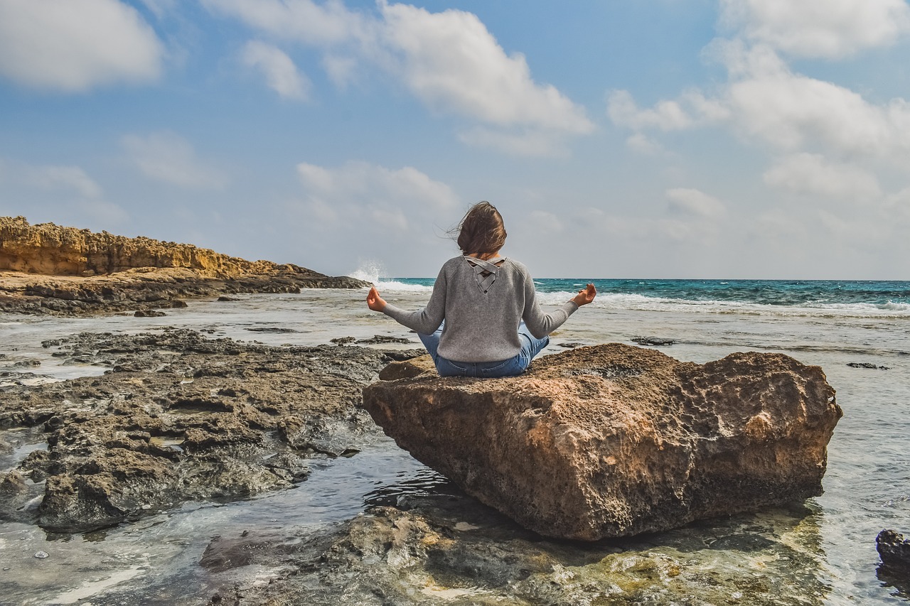 Femme pratiquant le yoga zen sur un rocher face à la mer